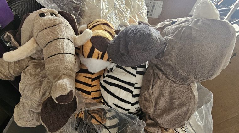 An elephant, a tiger, a zebra and a hippo soft toy lined up together, still part-wrapped.